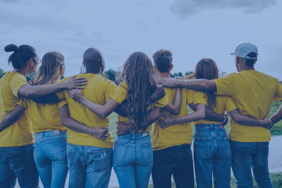 Gruppo di volontari abbracciati con magliette gialle